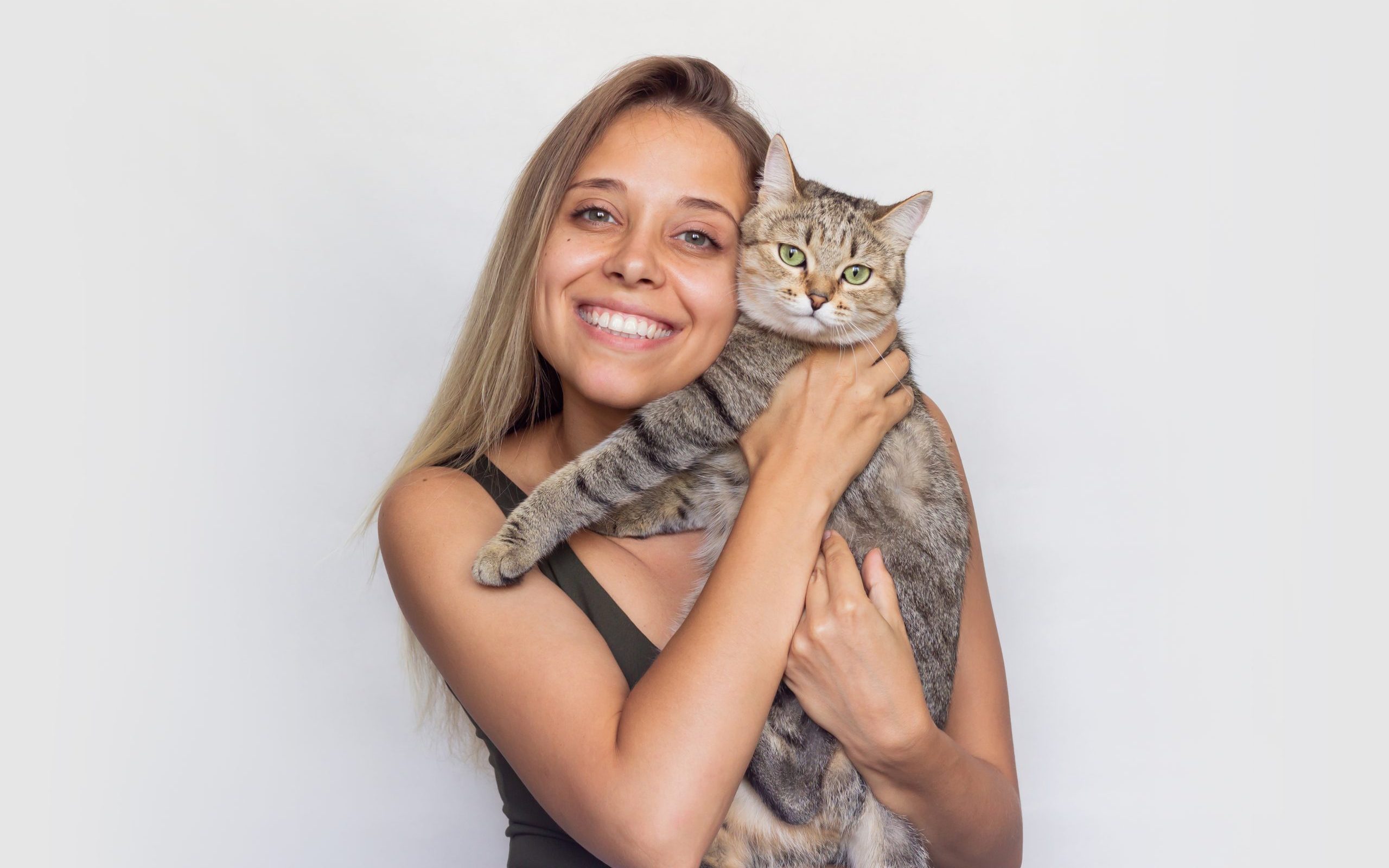 una-mujer-joven-sostiene-joven-gato-atigrado-en-sus-manos-aislado-sobre-un-fondo-blanco